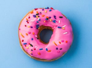 A pink frosted donut with sprinkles
